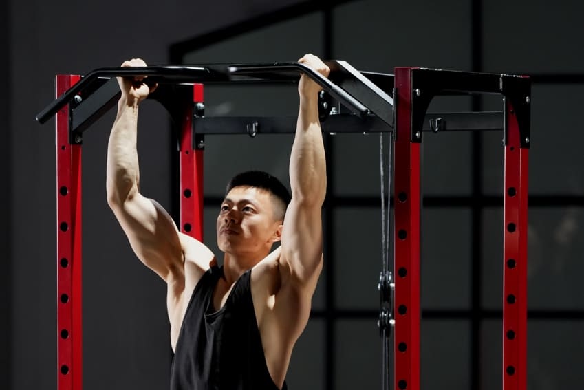 A man is doing chin-up by using the pull-up bar on power rack