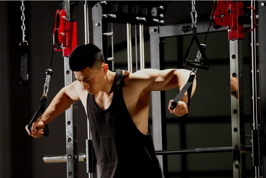 A man is using a smith machine to build his upper arm strength