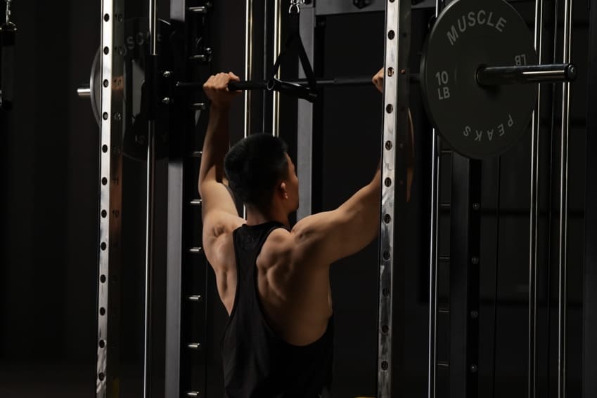 A man is lifting barbell on a black smith machine