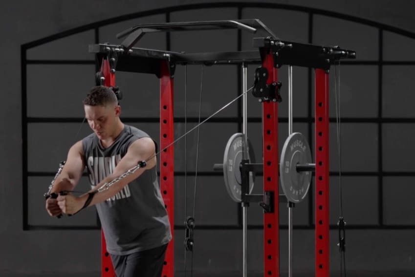 A man is using cable system to exercise his arms on power rack