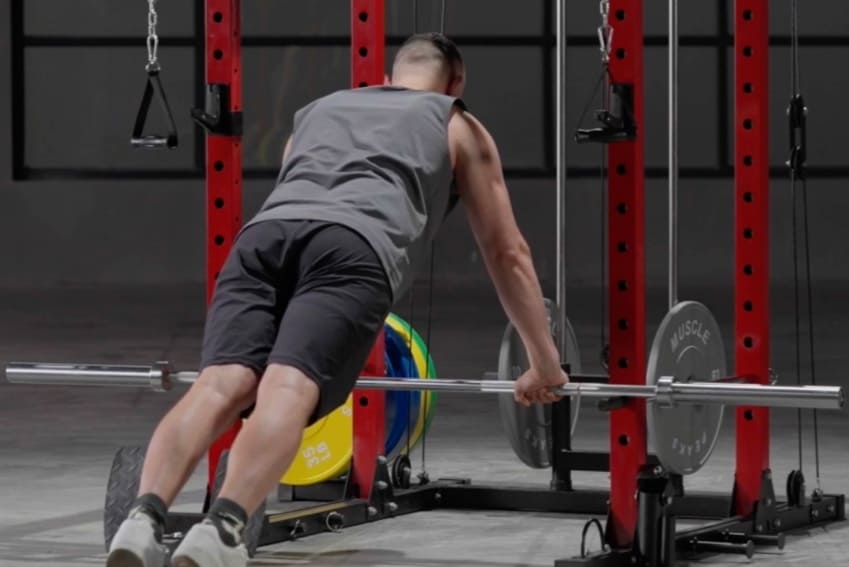 A man is woking out on the power rack