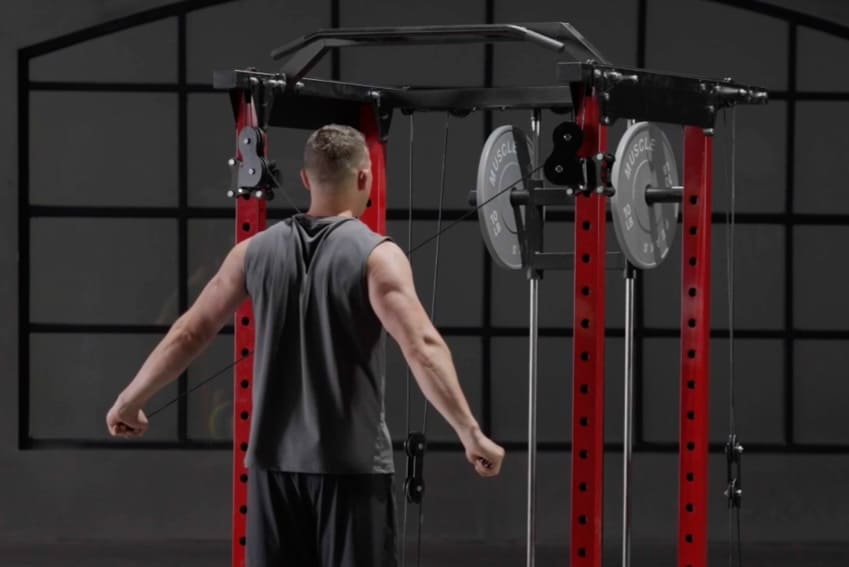 A man is using cable system to exercise his arm on power rack