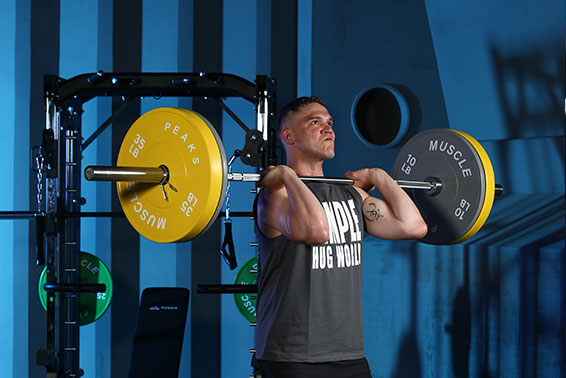 A man is lifting barball before the power rack