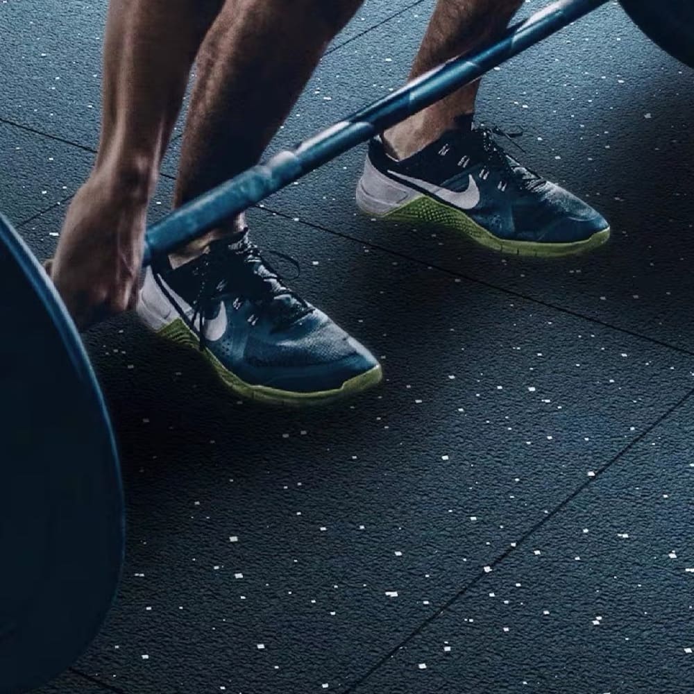 A man is lifting a barbell on a floor mat.