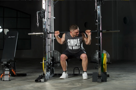 A man is lifting barbell on the smith machine