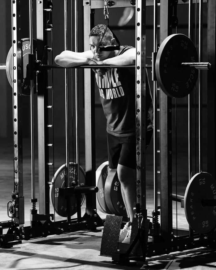 A man standing and leaning on a smith machine